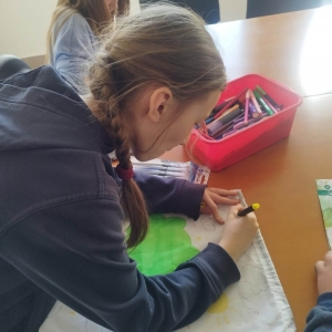 Uczestnicy zajęć kreatywnych podczas malowania worków szkolnych