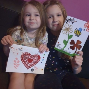 dwie dziewczynki pokazują własnoręcznie wykonane kartki  dla dziadków